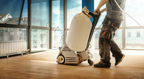 handyman using a vacuuming machine to cleanse floor in a spacious living room.