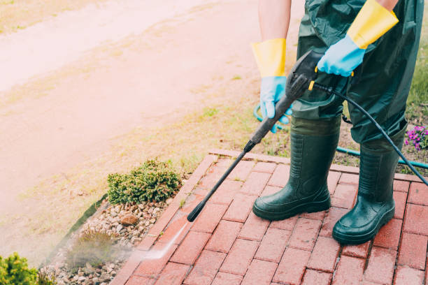 Man wearing waders, protective, waterproof trousers and gloves doing spring jobs outdoors.