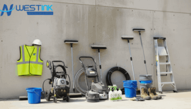 Exterior cleaning tools arranged beside a dusty building wall.
