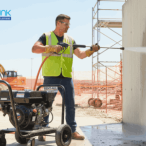 A construction worker safely operating a rented high-pressure washer to clean site surfaces